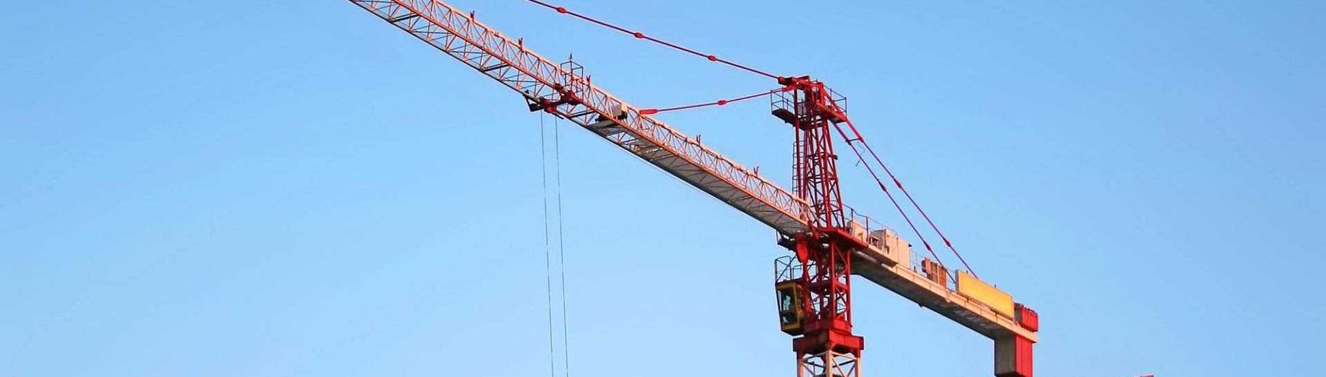 Tower crane on a high-rise building under construction at sunset, showcasing modern urban development.